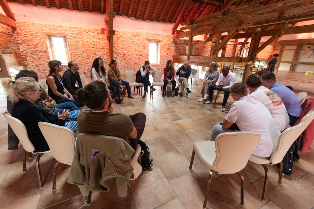 photo teambuiding Business seminar with a diverse group, featuring a speaker in a modern conference room.